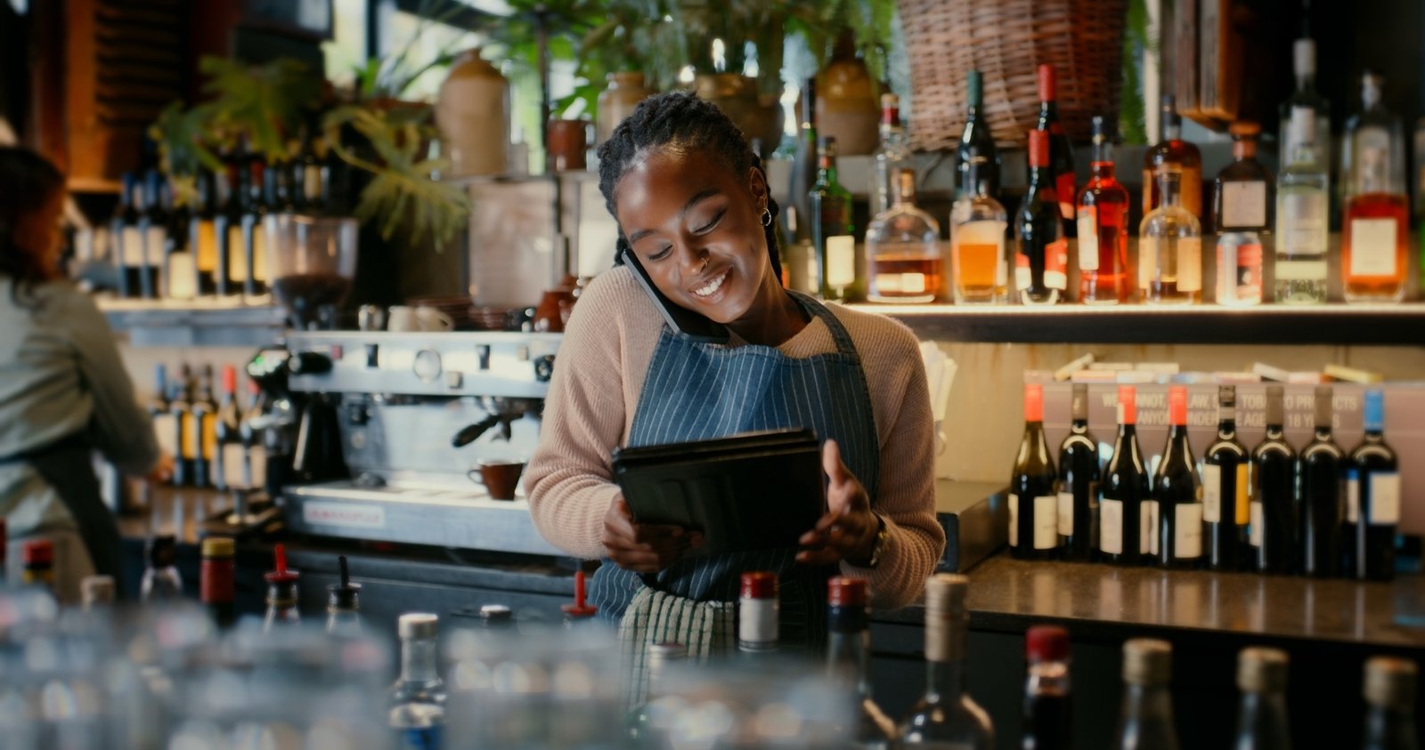 A bar worker smiling while taking an order on the phone