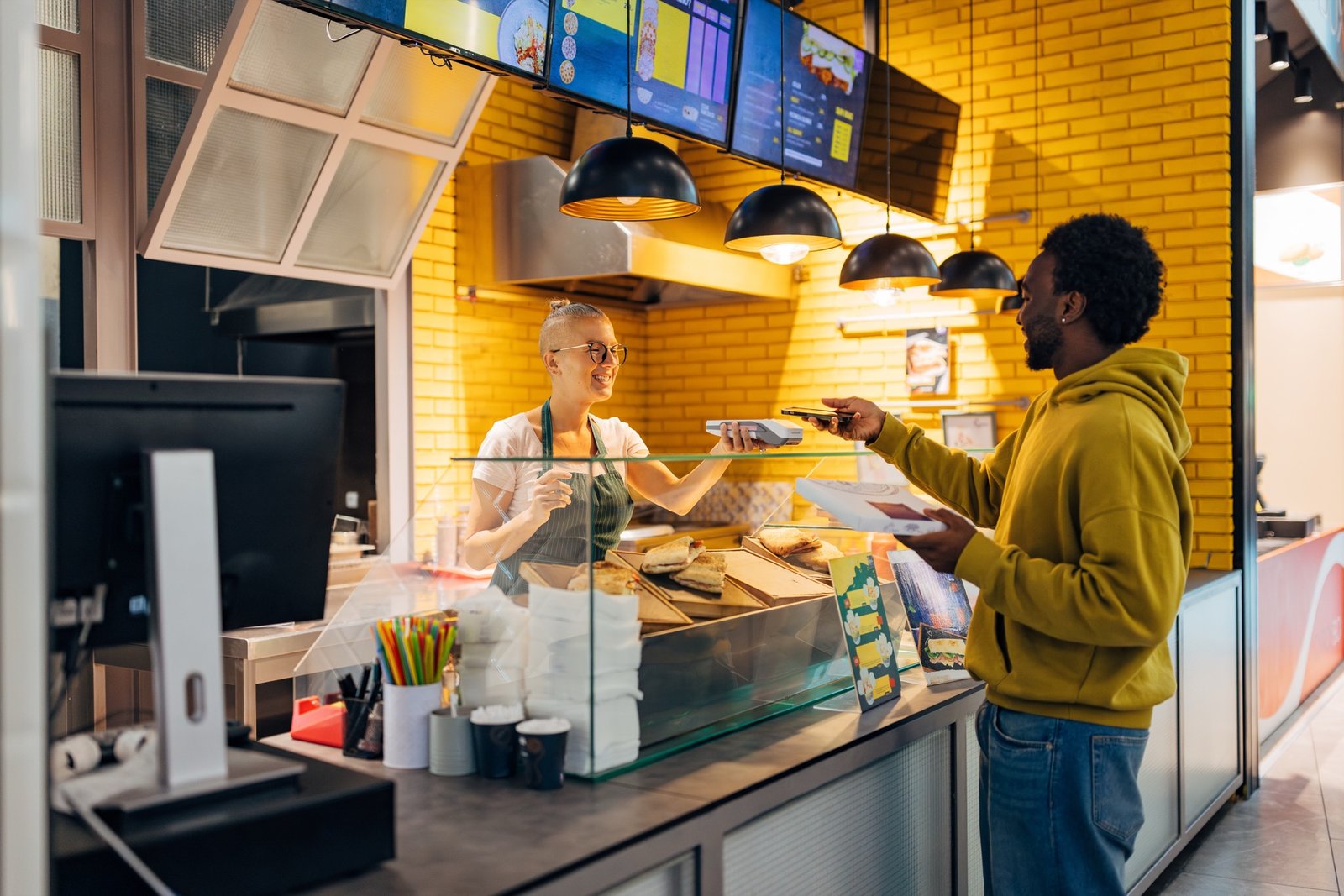 Two food service workers serving a customer at a counter